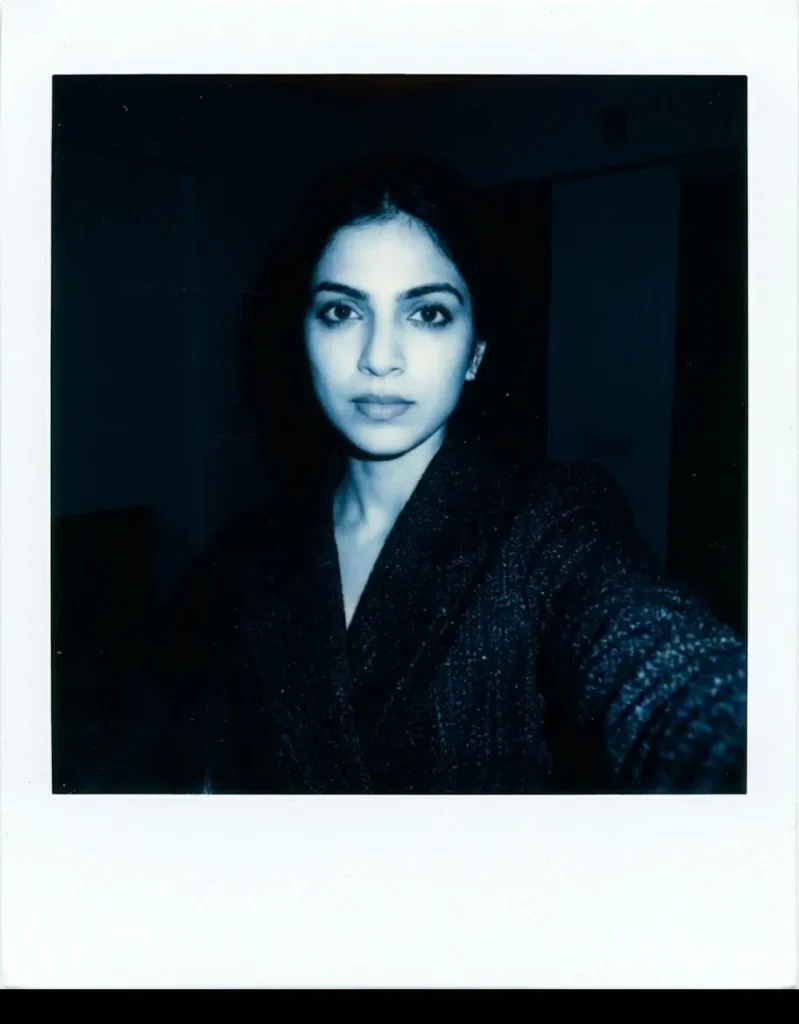 Realistic dark room flash polaroid of a young woman with gritty film grain, generated via Gemini AI